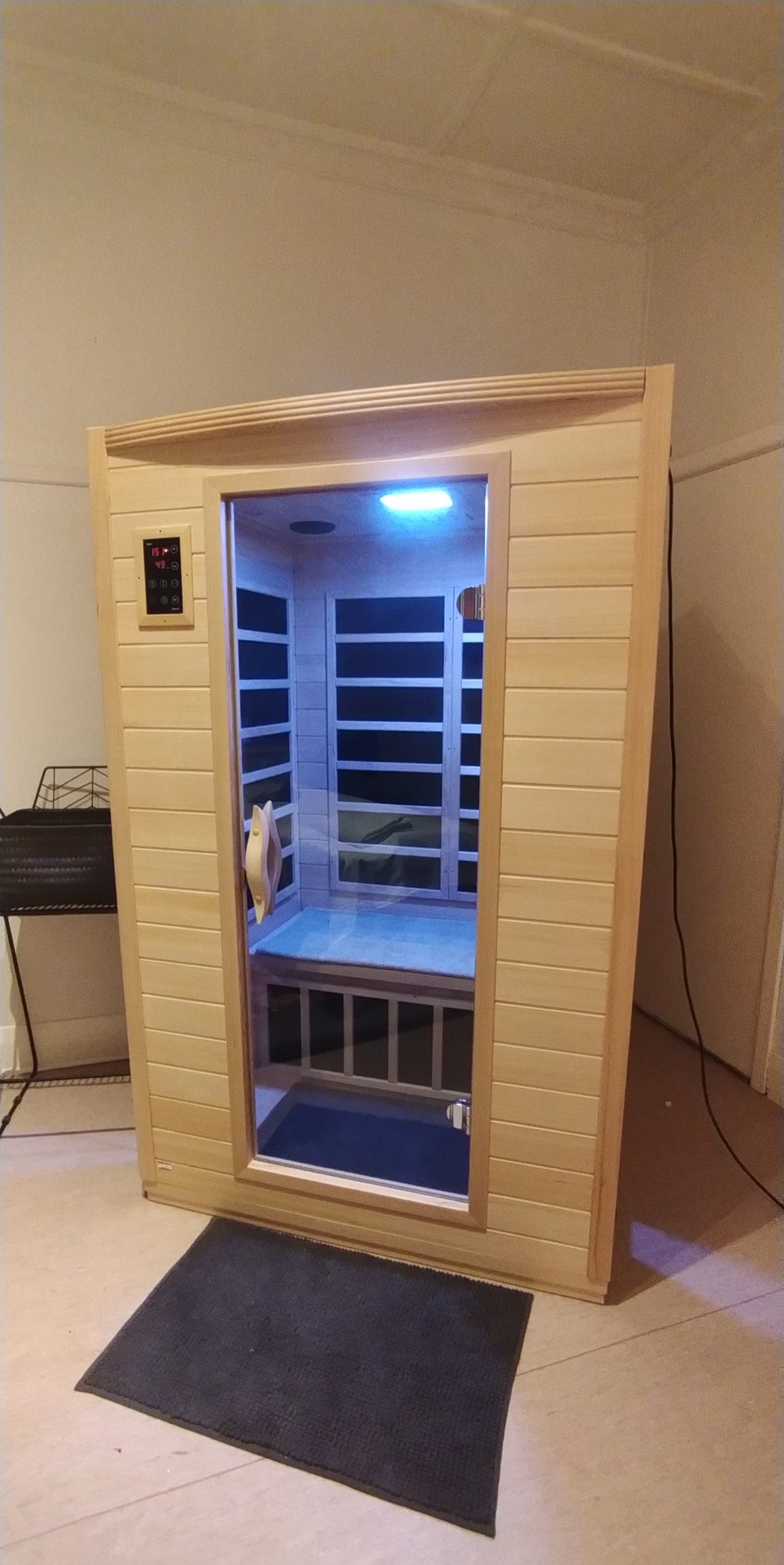 The timber infrared sauna cabin with its glass door and bench