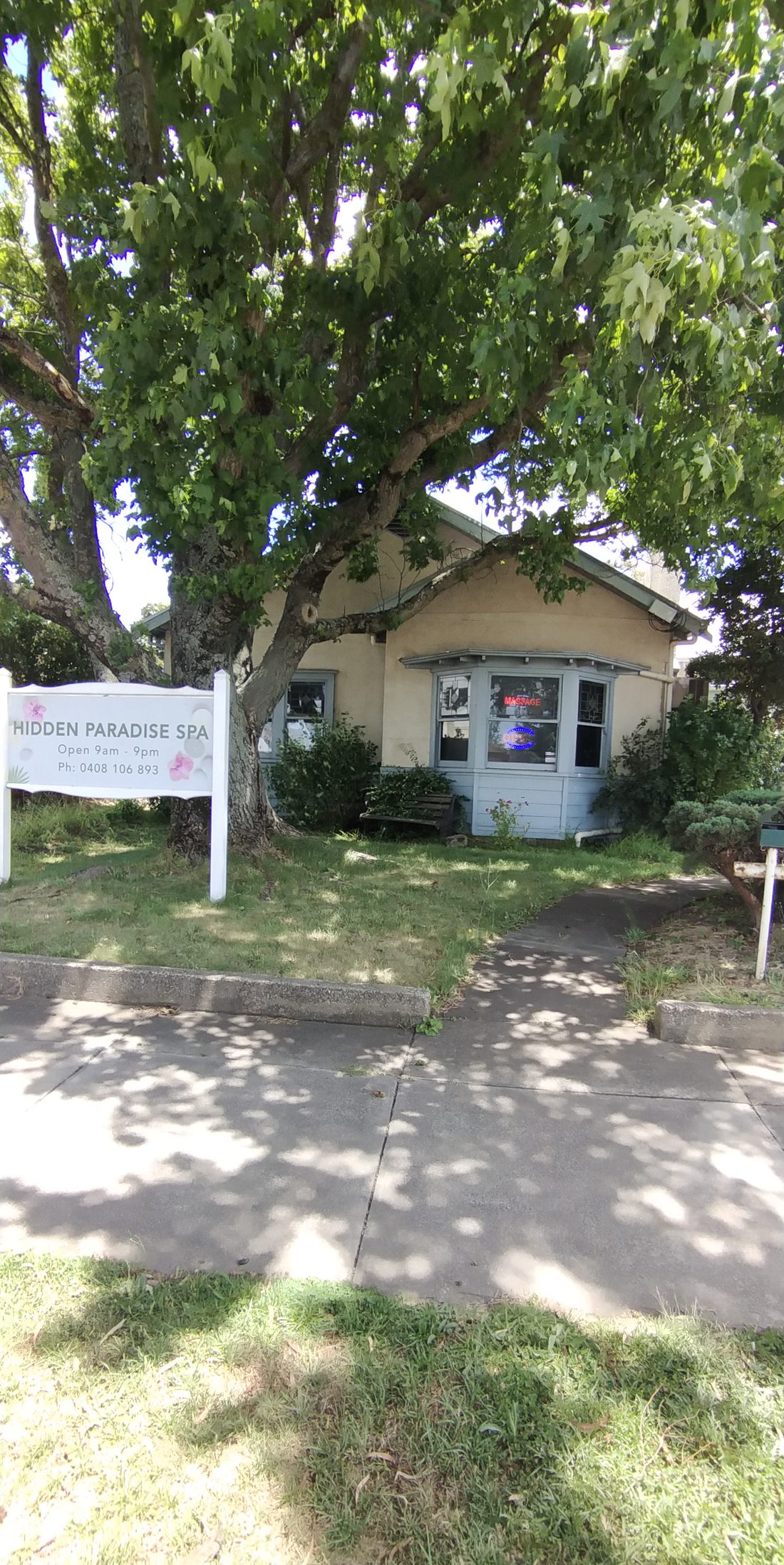 The Hidden Paradise Spa sign on the front lawn of the cottage at 172 Albert Street, under a big shady tree